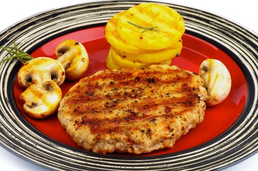 Roasted Turkey Steak with Grilled Sliced Potato and Portabello Mushrooms closeup on Striped Red Plate