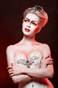 Red Queen with a crown and a corset, with make-up in studio shot