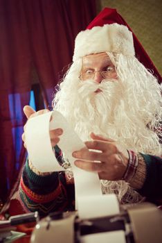 Shocked Santa Claus looking at receipts and bills during Christmas time