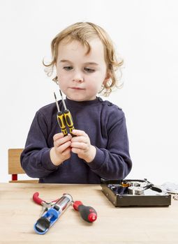 child choosing tool for repairing hard drive. Studio shot in gery background