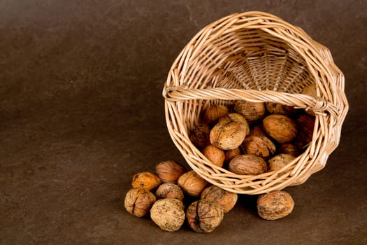 Walnuts in wicker basket on brown background