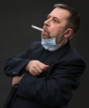 Illness. Man in medical mask with a thermometer