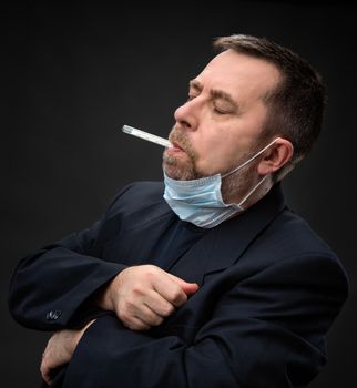 Illness. Man in medical mask with a thermometer