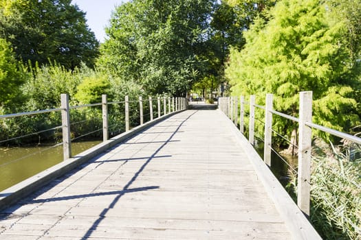 Wooden bridge in green garden in the afternoon