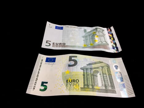 Old and new five Euro bills towards black background