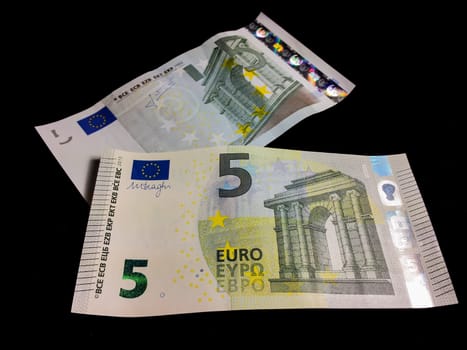 Old and new five Euro bills towards black background