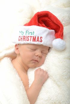 newborn infant and first Christmas in a red santa hat