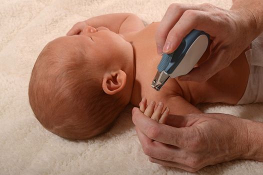 mother cutting baby nails with fingernail clippers