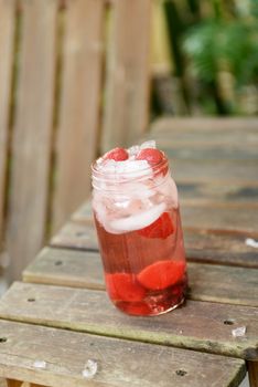 summer cocktail with strawberries and ice in mason jar
