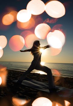 warrior II yoga pose on beach with sunrise and flares