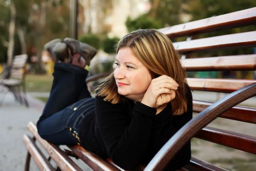 Young women lies on a bench in a park