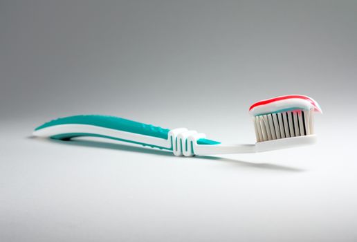 Colored toothpaste at a toothbrush at light background