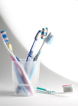 Some toothbrushes in a plastic glass