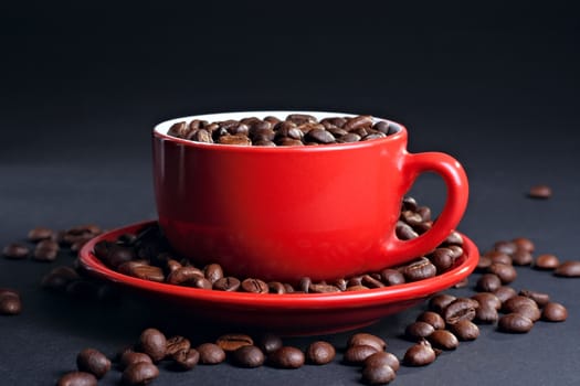 Cup on the saucer with coffee beans at the dark background