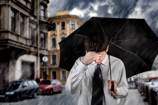 Sad Young Man walking with Umbrella under the Rain in the City