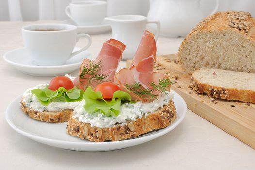 breakfast with a cup of coffee and a sandwich of whole grain bread with ricotta and ham

