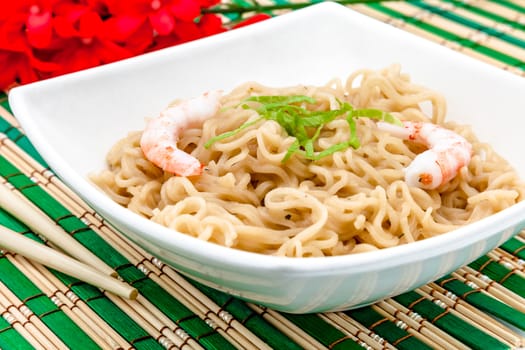 Composition of a bowl of noodles with shrimps on a bamboo table