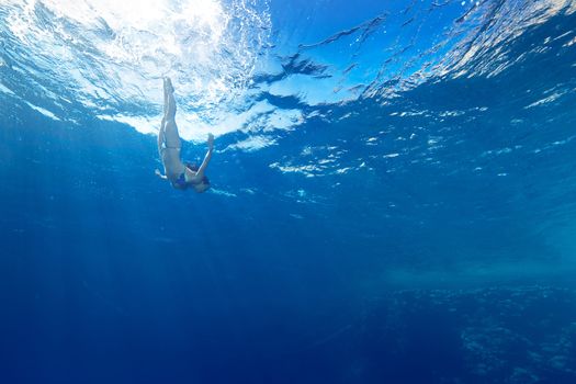 athletic girl diving under the sea