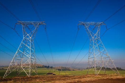 Electricity cables attached to steel structure towers transport electrical power supply over the countryside landscape