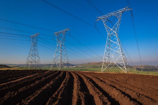 Electricity cables attached to steel structure towers transport electrical power supply over the countryside landscape