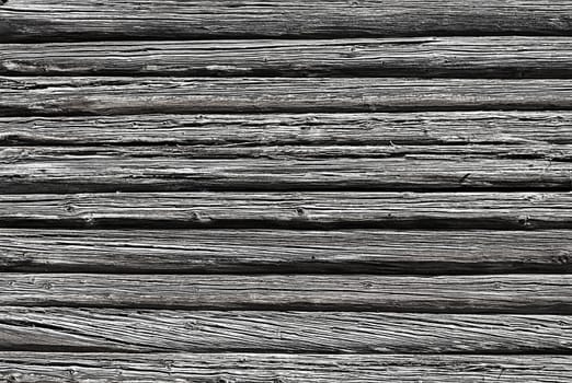 Wall of old weathered logs with cracks, black and white