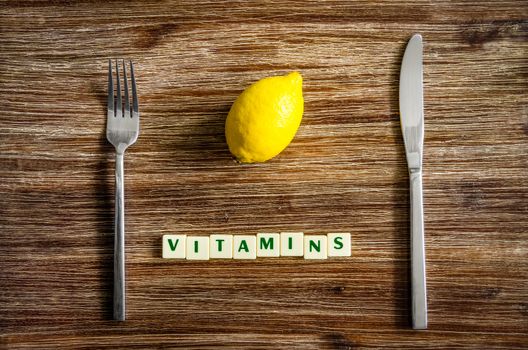 Silverware and lemon set on wooden vintage table with sign Vitamins