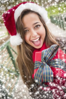 Pretty Festive Smiling Woman Wearing a Christmas Santa Hat with Bow Wrapped Gift Outside with Snow Flakes Border.