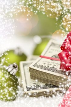 Stack of One Hundred Dollar Bills with Red Bow Near Green Christmas Ornaments on Snow Flakes with Snow Flake Border.