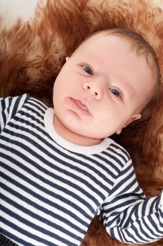 Shot of newborn baby lying on fur and watching on you