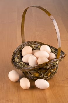 Fresh eggs in a basket on a wooden background