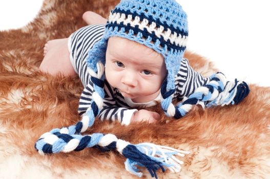 Shot of newborn baby in funny hat lying on fur