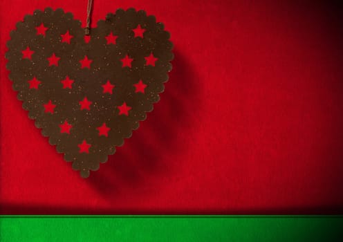 Metal heart with stars hanging on red and green velvet background with shadows