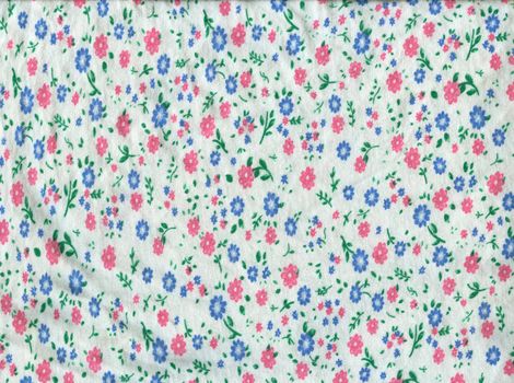 Texture of white knitted fabric in small pink and blue flowers