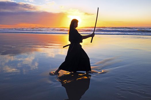 Young samurai women with Japanese sword(Katana) at sunset on the beach