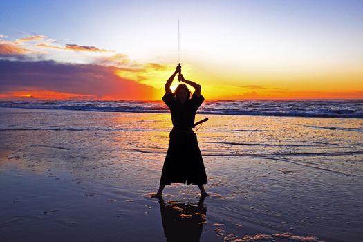 Young samurai women with Japanese sword(Katana) at sunset on the beach