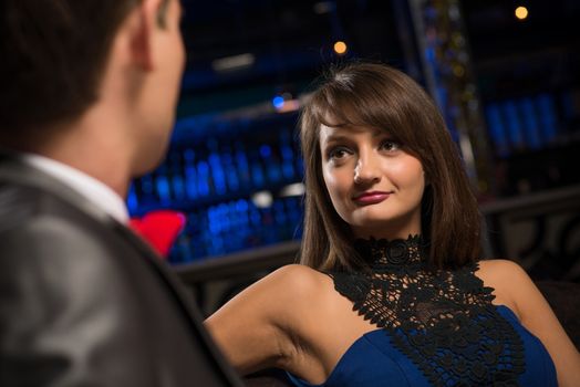 portrait of a woman in a nightclub, sitting on the couch and talking with man