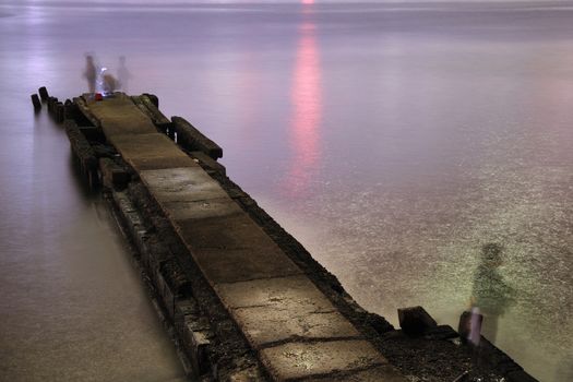 night pier with fishermans shadows taken on long exposure
