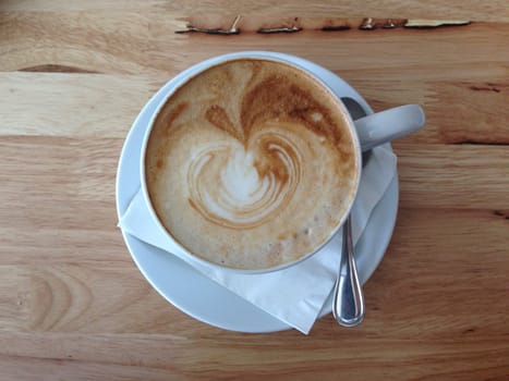 a cup of latte on a wood table