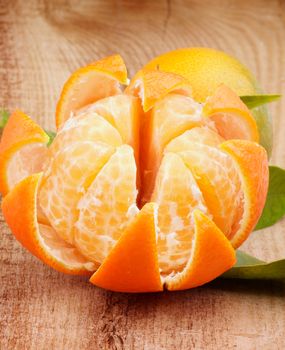 Fresh Ripe Tangerine with Segments and Citrus Peel closeup on Wooden background