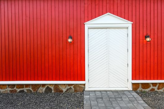Red wooden wall and frnt white doors with two porch lamps