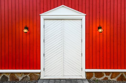 Red wooden wall and white doors with two porch lamps