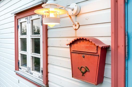 Red mail box, window and lamp on a white wooden house