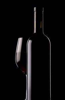 Glass and bottle of red wine on black background