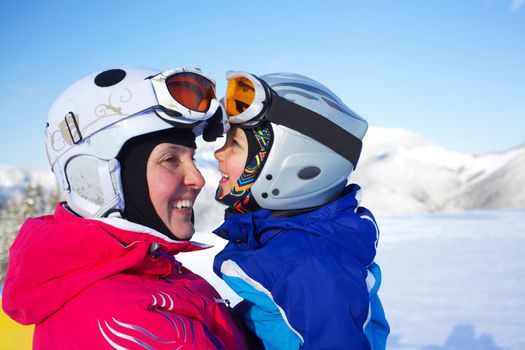 Happy little boy to ski in ski goggles and a helmet with his mother