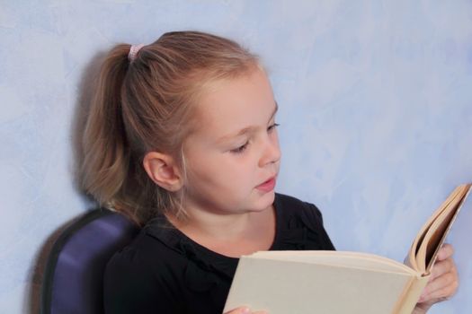 Portrait of girl with blond hair reading a book