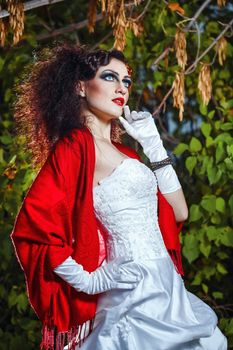 Attractive bride in a wedding dress with bright makeup, red shawl