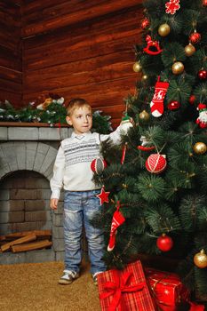 Boy shot on background with Christmas tree, gifts and fireplace