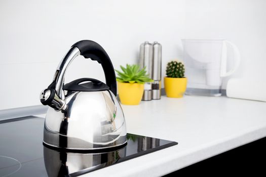 Steel kettle in modern kitchen with induction stove 