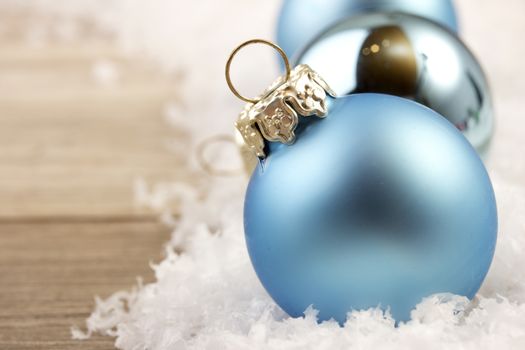 christmas decoration with wooden background, snow, christmas baubles blue and silver 