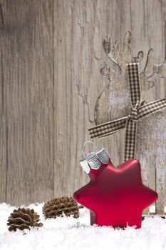christmas decoration with wooden background, snow, christmas baubles red, elk and pine cones 